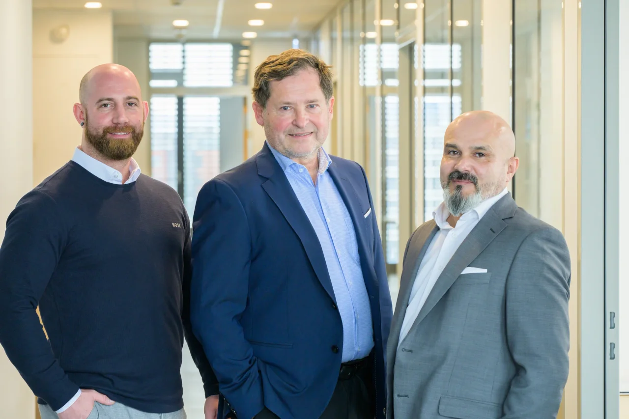 Three members of the pacon management team in a bright office corridor